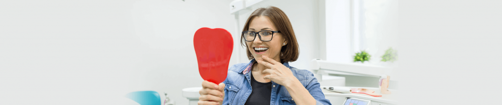 Happy woman looking at her smile in the mirror