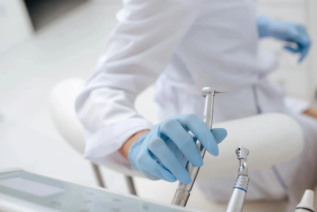Unrecognized dentist in Franklinville, NJ, holding instrument in room.